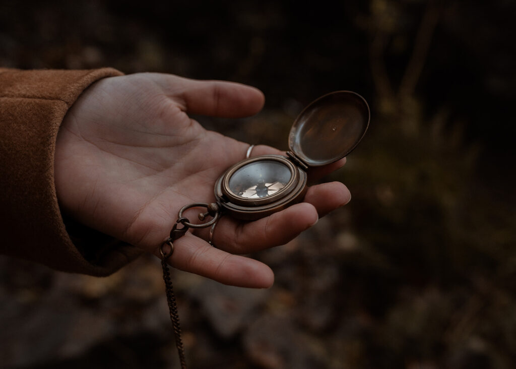 Hand holding a gold compass, to represent the power of a reset day in your photography business